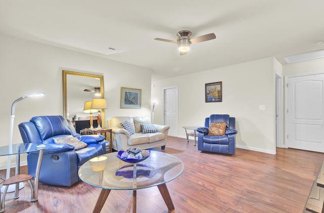 living room featuring ceiling fan, baseboards, and wood finished floors