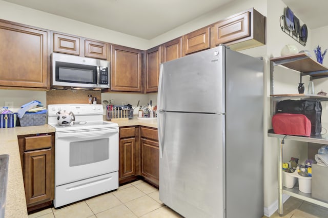 kitchen featuring brown cabinets, stainless steel appliances, light countertops, and light tile patterned flooring