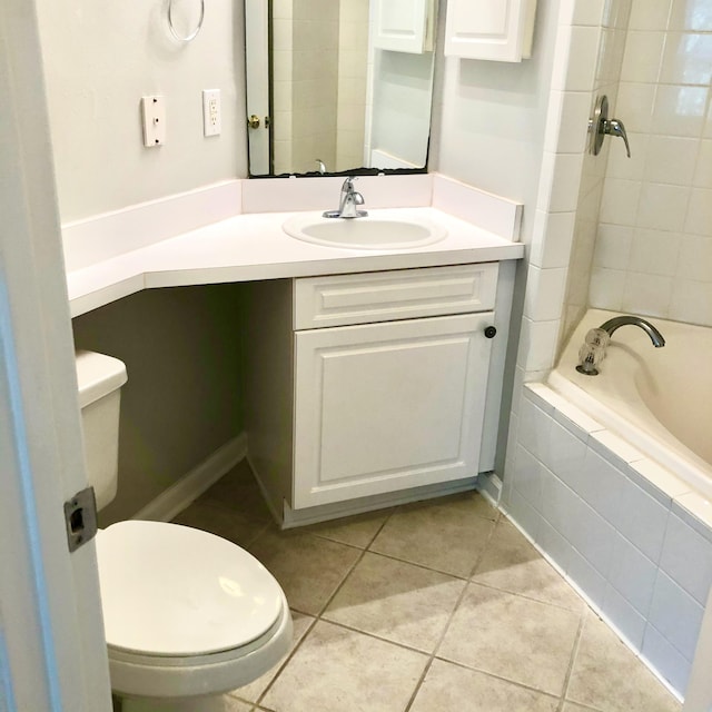 bathroom with toilet, vanity, tiled bath, and tile patterned floors