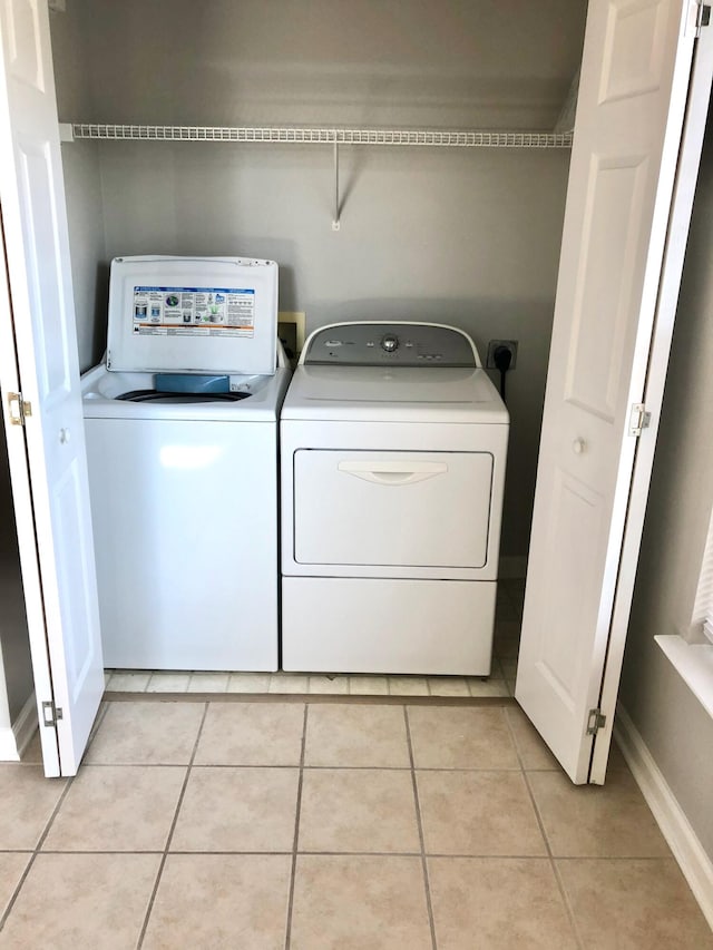 clothes washing area featuring independent washer and dryer and light tile patterned flooring