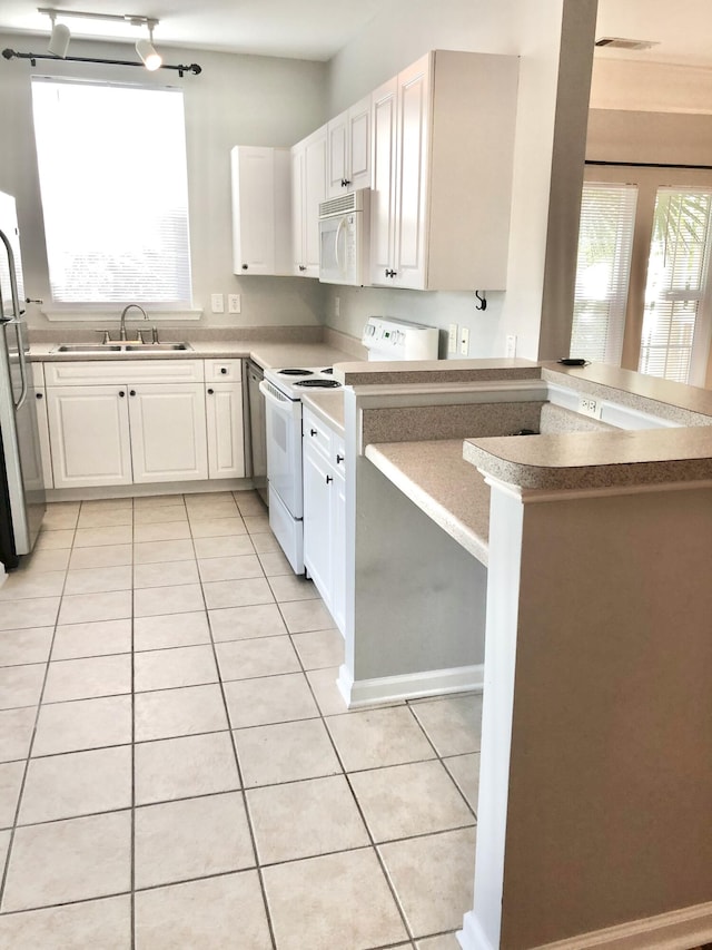 kitchen with sink, white appliances, kitchen peninsula, and a wealth of natural light