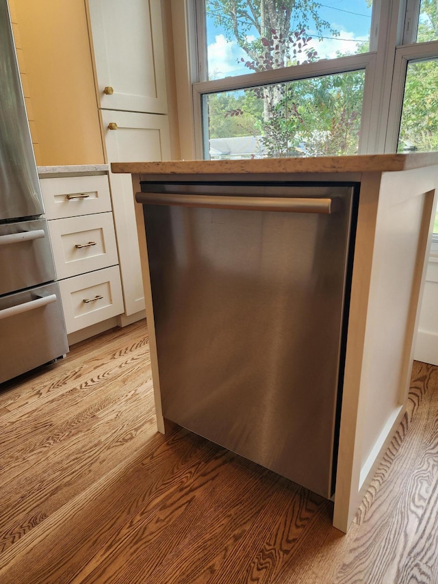 interior details featuring light wood-type flooring, white cabinetry, and stainless steel appliances