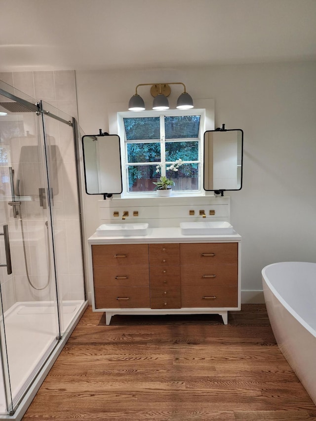 bathroom with plus walk in shower, hardwood / wood-style floors, and vanity