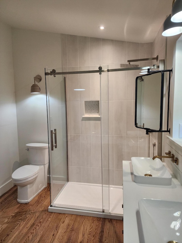 bathroom with hardwood / wood-style flooring, toilet, a shower with shower door, and sink