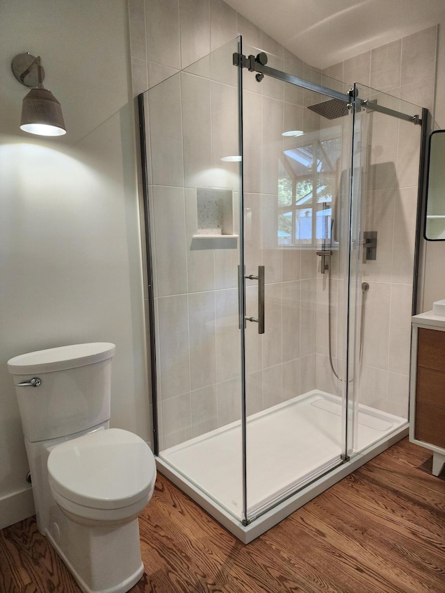 bathroom featuring wood-type flooring, vanity, toilet, and a shower with door