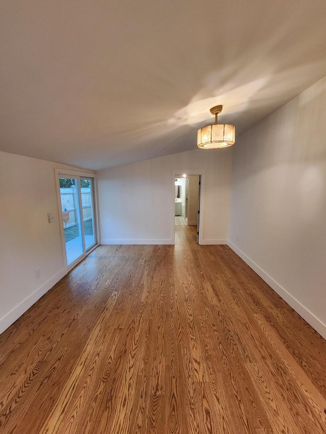 spare room featuring wood-type flooring and lofted ceiling