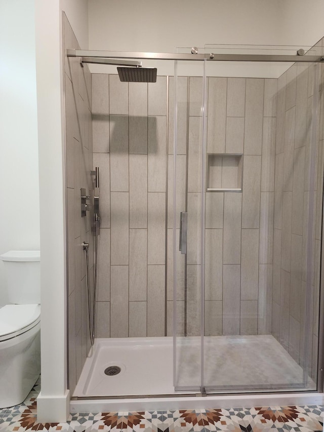 bathroom featuring tile patterned flooring, toilet, and a shower with shower door