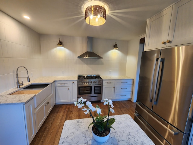 kitchen with sink, wall chimney exhaust hood, decorative backsplash, appliances with stainless steel finishes, and white cabinetry