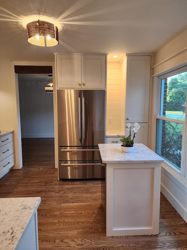 kitchen featuring dark hardwood / wood-style flooring, white cabinetry, stainless steel refrigerator, and light stone counters