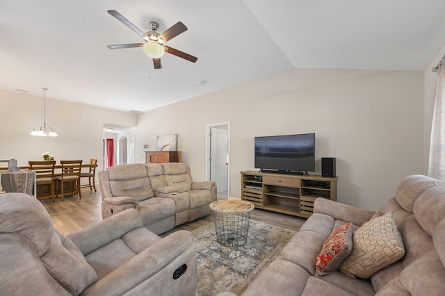 living room featuring lofted ceiling, ceiling fan with notable chandelier, and light hardwood / wood-style flooring