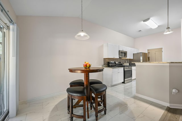 kitchen featuring stainless steel appliances, vaulted ceiling, hanging light fixtures, and white cabinets