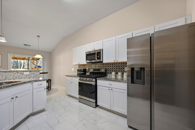 kitchen with stainless steel appliances, dark stone countertops, pendant lighting, and white cabinets