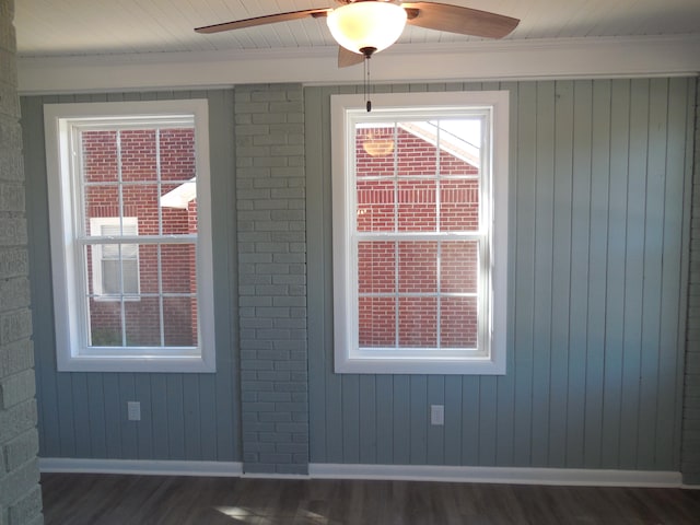 unfurnished room with dark wood-type flooring, ceiling fan, crown molding, and wood walls