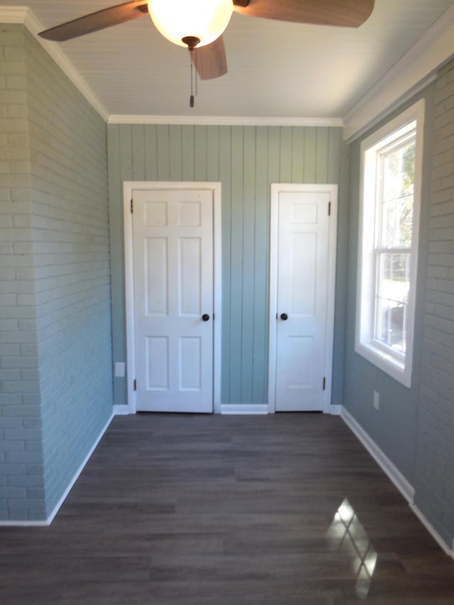 unfurnished bedroom with ornamental molding, brick wall, dark hardwood / wood-style floors, and ceiling fan