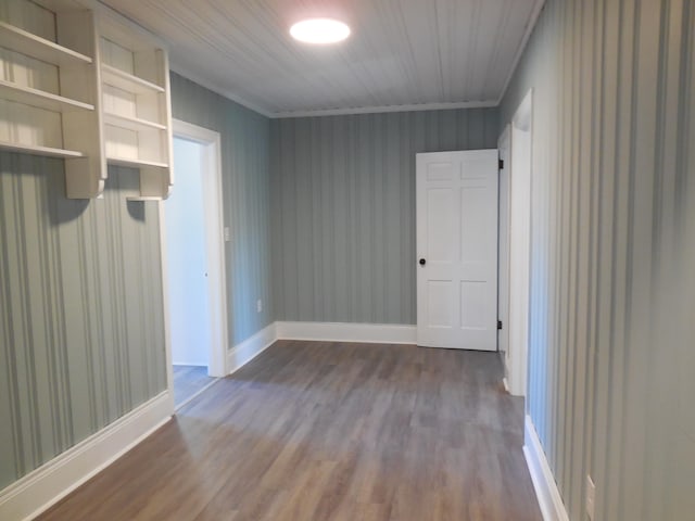 empty room featuring crown molding, hardwood / wood-style flooring, and built in features