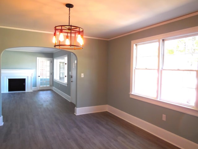 unfurnished dining area with an inviting chandelier, crown molding, dark hardwood / wood-style floors, and a healthy amount of sunlight