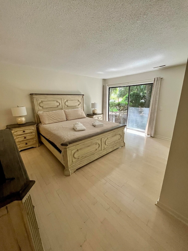 unfurnished bedroom with a textured ceiling, light hardwood / wood-style flooring, and access to exterior