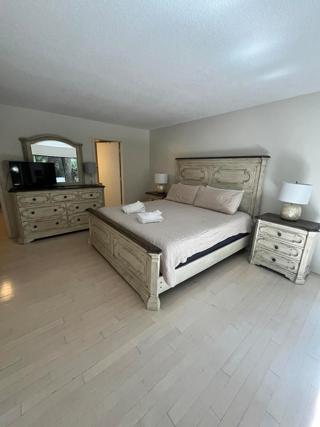 bedroom with light hardwood / wood-style flooring and a textured ceiling