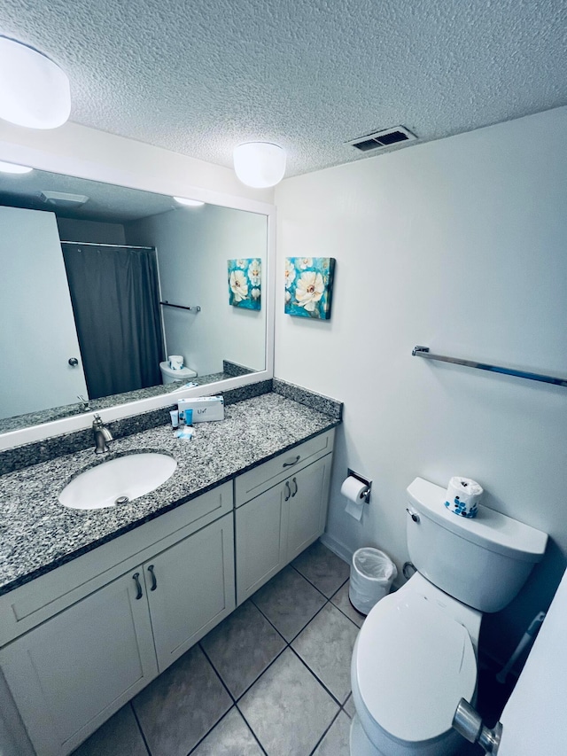 bathroom featuring a textured ceiling, vanity, toilet, and tile patterned floors