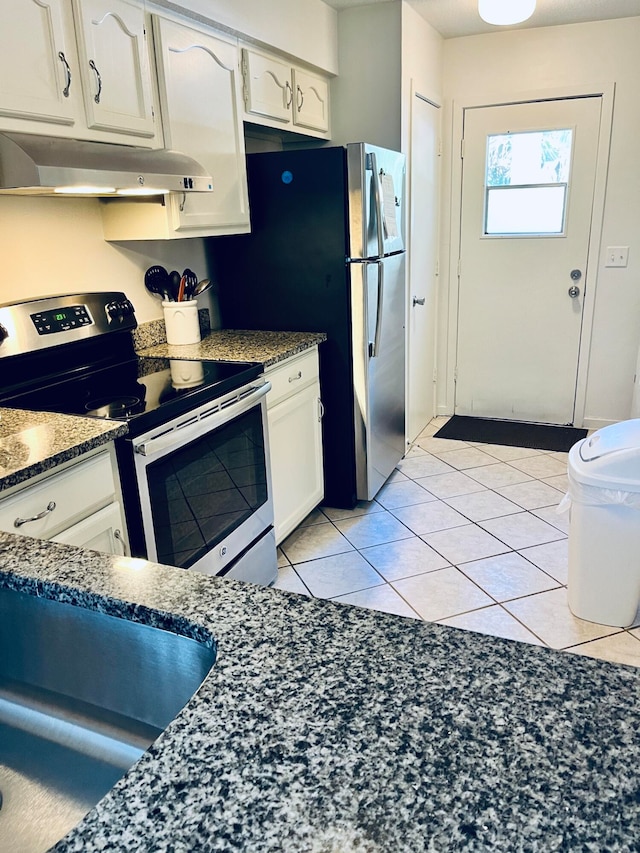 kitchen with white cabinets, light tile patterned flooring, appliances with stainless steel finishes, and dark stone counters