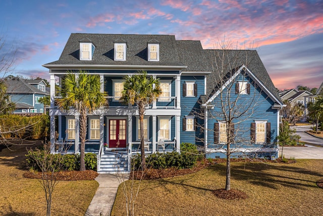 view of front of home with a balcony, a porch, roof with shingles, french doors, and a front lawn