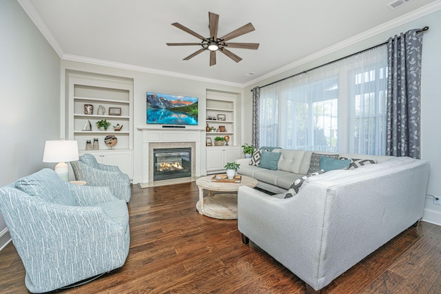 living area featuring built in features, visible vents, a fireplace with flush hearth, ornamental molding, and wood finished floors