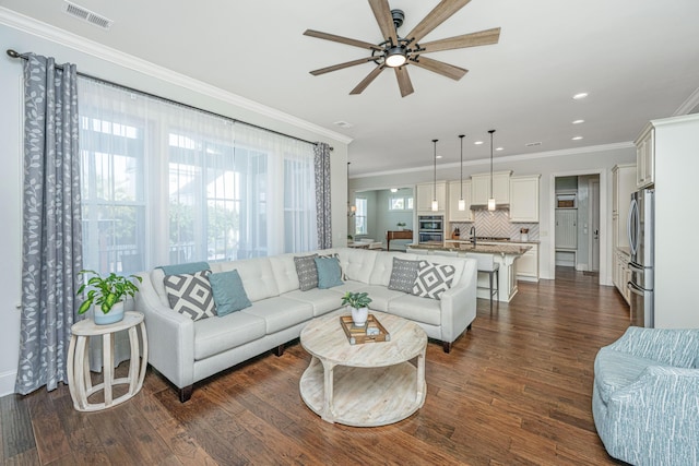 living area featuring dark wood-style floors, recessed lighting, visible vents, and ornamental molding