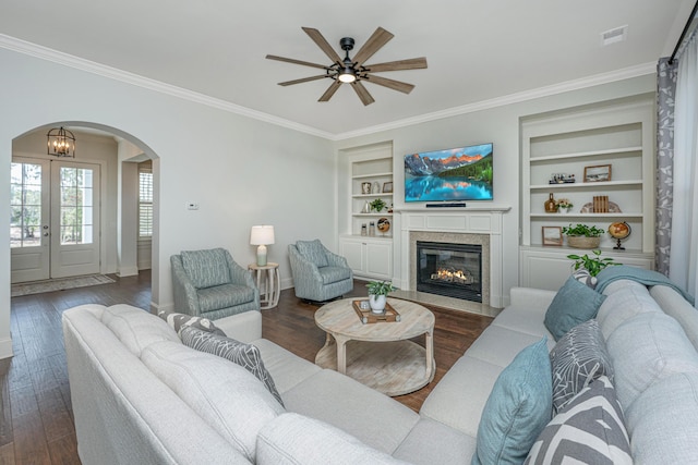 living room with visible vents, arched walkways, dark wood finished floors, built in features, and ornamental molding