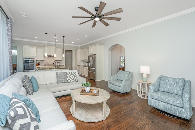 living area with arched walkways, visible vents, baseboards, ornamental molding, and dark wood finished floors