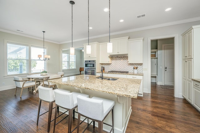 kitchen with under cabinet range hood, stainless steel appliances, a sink, visible vents, and crown molding