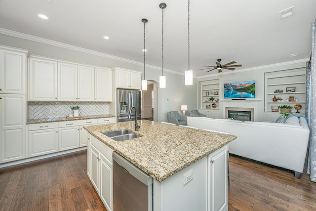 kitchen with visible vents, arched walkways, a glass covered fireplace, appliances with stainless steel finishes, and a sink