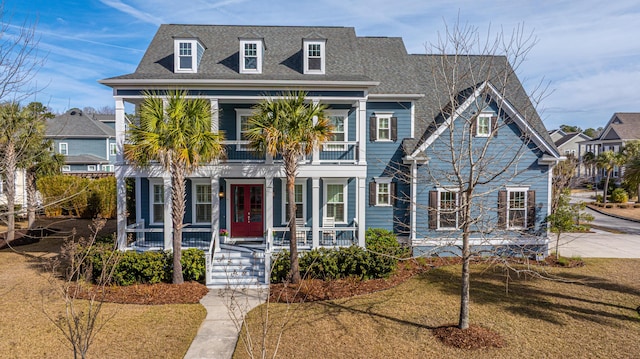 view of front of property featuring covered porch, a front lawn, roof with shingles, and a balcony