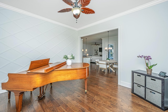 office with baseboards, an accent wall, ornamental molding, wood finished floors, and ceiling fan with notable chandelier