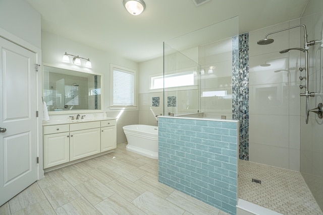 full bathroom with a walk in shower, a freestanding tub, and vanity