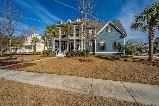 view of front facade with a balcony, a front lawn, and a porch