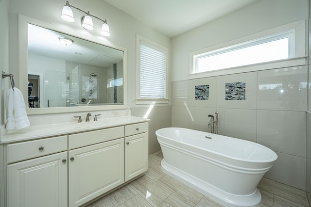 full bath with a shower stall, a freestanding bath, tile walls, and vanity