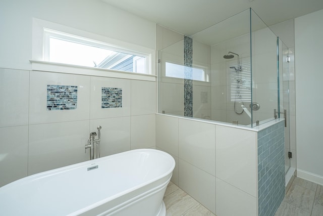 full bath with a stall shower, a freestanding tub, and tile walls