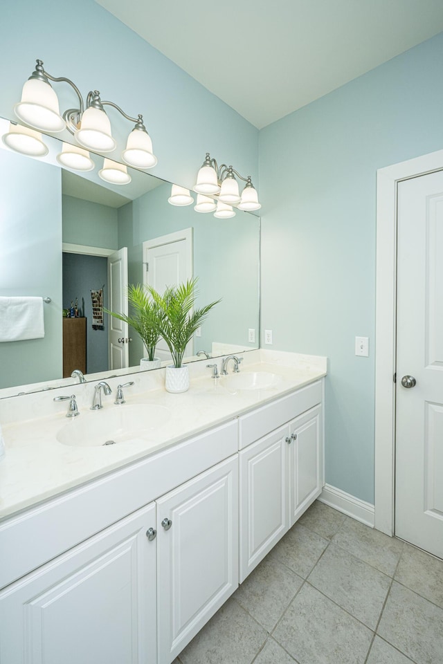 bathroom with double vanity, tile patterned flooring, a sink, and baseboards