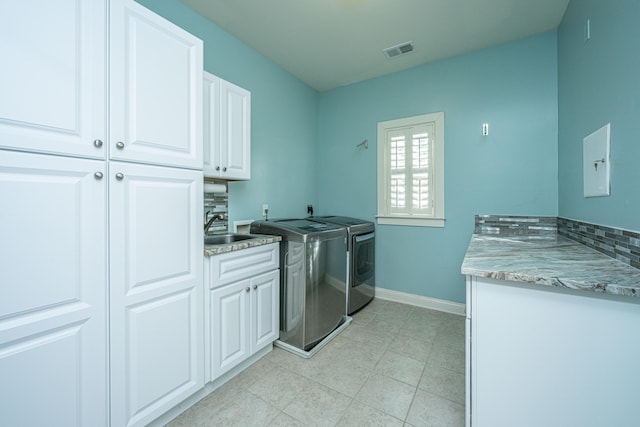 clothes washing area featuring cabinet space, baseboards, visible vents, independent washer and dryer, and a sink