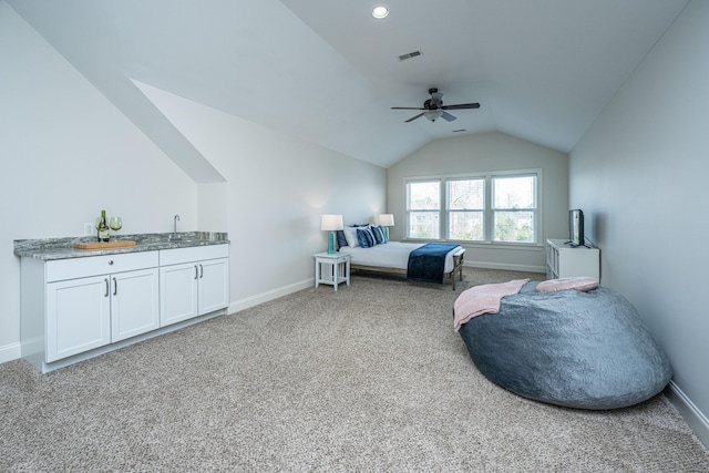 carpeted bedroom featuring lofted ceiling, a sink, visible vents, baseboards, and wet bar