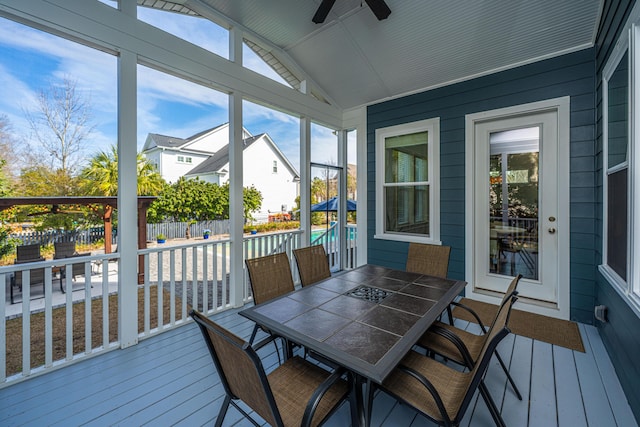 sunroom with plenty of natural light, a residential view, vaulted ceiling, and a ceiling fan