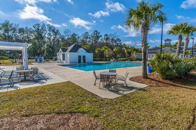 pool with a lawn, an outbuilding, a storage structure, fence, and a patio area