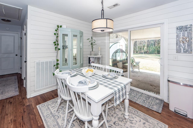 dining space with dark hardwood / wood-style flooring and wood walls