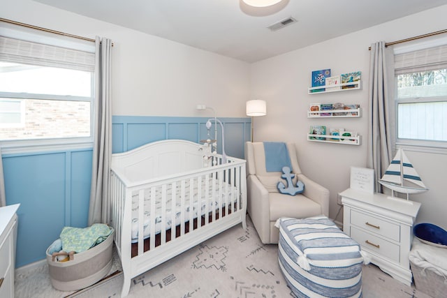 bedroom with light carpet and a nursery area