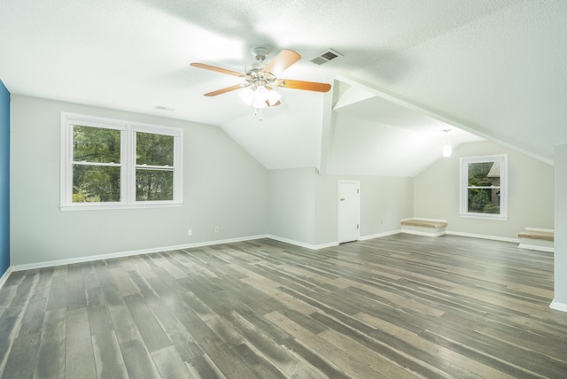 additional living space with a textured ceiling, dark wood-type flooring, ceiling fan, and vaulted ceiling