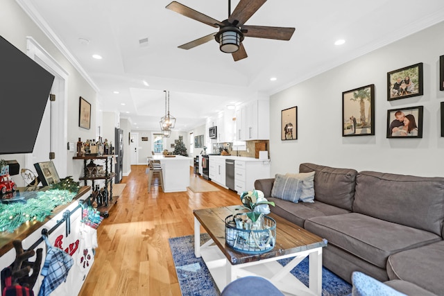 living room with light wood-type flooring, ceiling fan, and ornamental molding