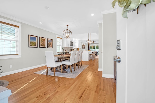 dining space with light hardwood / wood-style floors, crown molding, and a notable chandelier