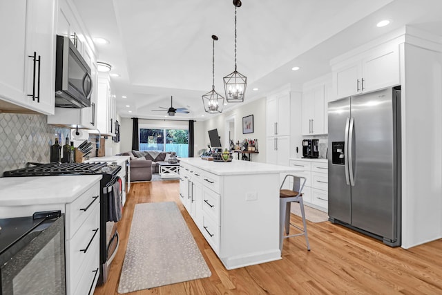 kitchen featuring white cabinetry, stainless steel appliances, light hardwood / wood-style flooring, a kitchen bar, and a kitchen island