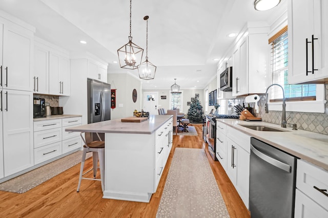 kitchen with white cabinets, stainless steel appliances, light hardwood / wood-style floors, and sink