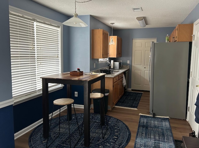 kitchen with dark hardwood / wood-style flooring, decorative light fixtures, stainless steel refrigerator, and a textured ceiling